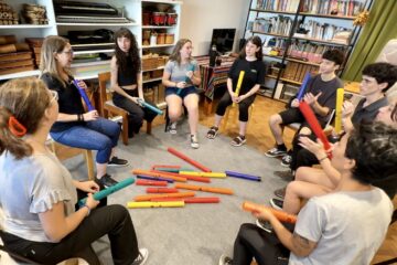 Grupo de estudiantes en ronda usando Boomwhackers en clase de música